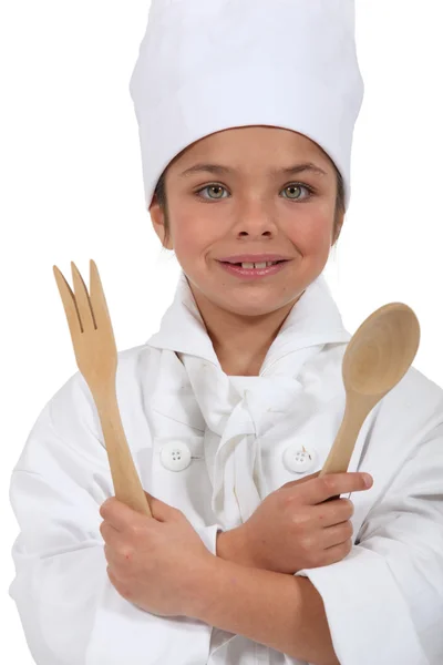 Adolescente chica vestida con traje de cocinero sosteniendo cuchara de madera y tenedor — Foto de Stock
