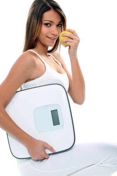 Mulher jovem e magra com uma maçã e uma balança de banheiro — Fotografia de Stock