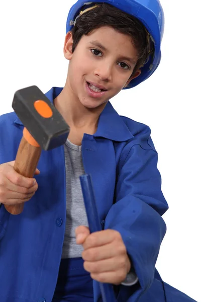 Un niño vestido de trabajador de la construcción con un martillo . —  Fotos de Stock