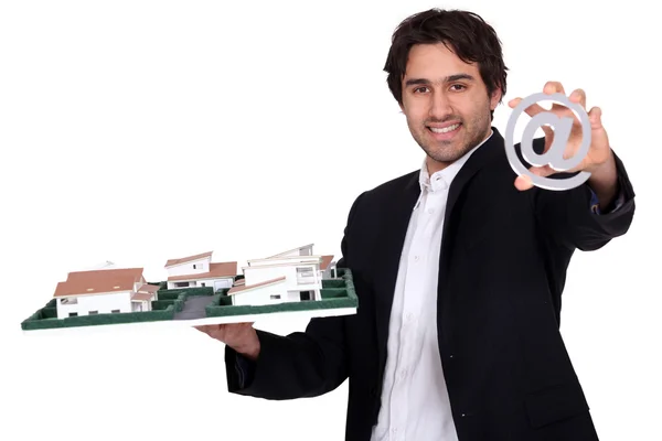 Architect with a model of a housing estate and an @ sign — Stock Photo, Image