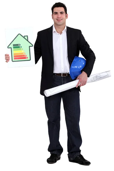 Engineer holding a hard hat, a rolled-up drawing and an energy efficiency rating sign — Stock Photo, Image