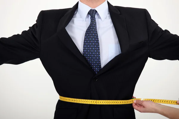Businessman with a tape measure round his waist — Stock Photo, Image