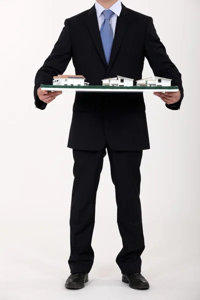 Businessman holding a model of a housing estate — Stock Photo, Image