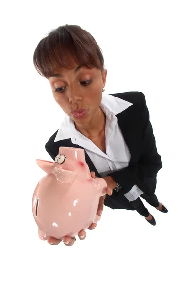 Mulher de negócios olhando para um banco porquinho — Fotografia de Stock