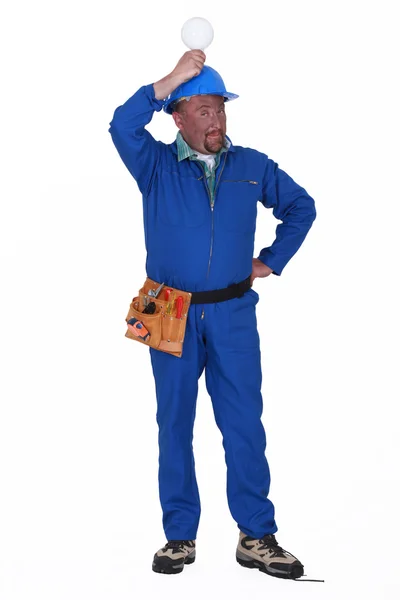 Electricista sosteniendo una bombilla sobre su cabeza — Foto de Stock