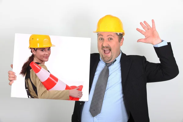 Site's foreman open-mouthed holding picture of woman with construction cone — Stock Photo, Image