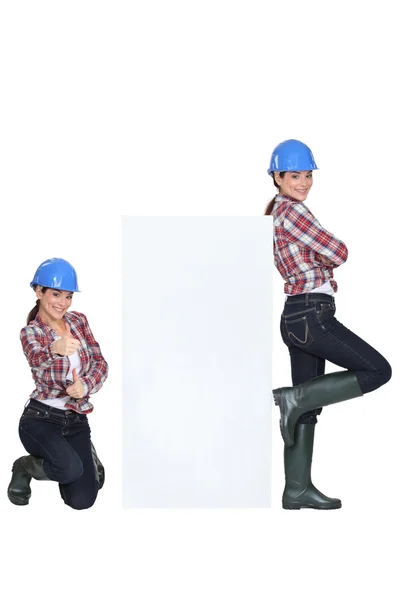 Flickor som bär blå hård hatt slående en pose — Stockfoto