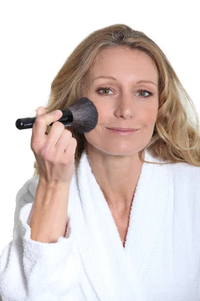 Woman in bathrobe using blusher brush — Stock Photo, Image