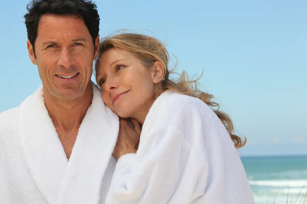 Paar in badjassen op het strand — Stockfoto