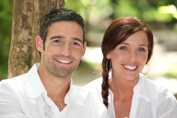 Couple in front of a tree trunk — Stock Photo, Image