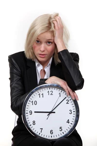 Stressed blond woman with clock Stock Photo