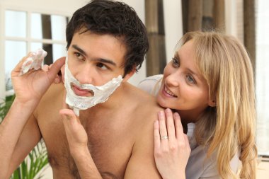 Woman looking at man shaving clipart