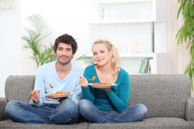 Couple having dinner on their couch clipart