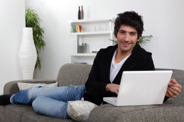 Man lying on sofa with computer clipart