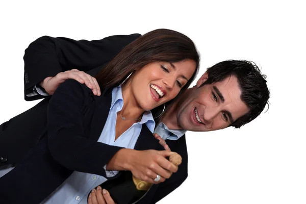 Businessman and businesswoman celebrating with bottle of champagne — Stock Photo, Image