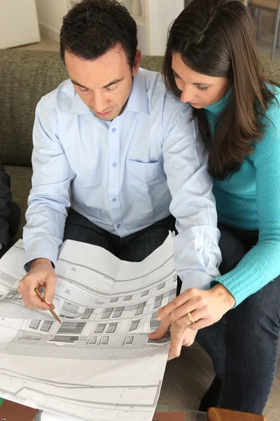 Paar untersucht einen Bauplan — Stockfoto