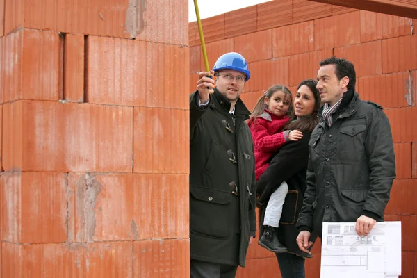 Empresario inmobiliario y una familia en una obra de construcción — Foto de Stock