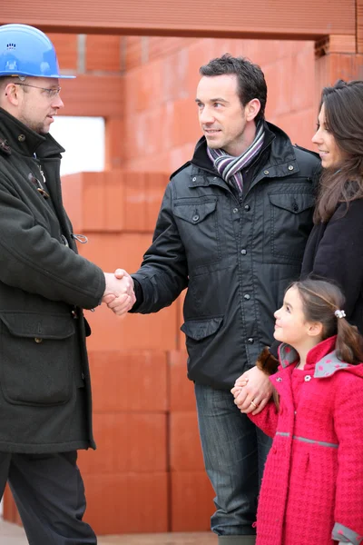 Architect shaking hands with a young family on site — Stock Photo, Image