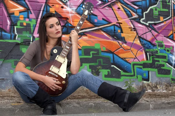Woman with guitar in front of painted wall — Stock Photo, Image