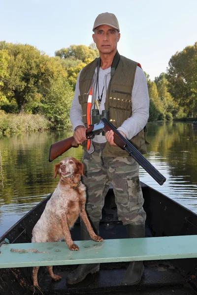 Охотник с собакой на лодке — стоковое фото