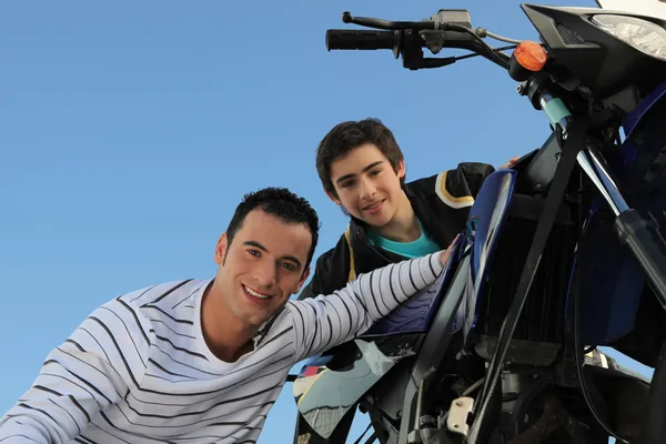 Мужчина и подросток смотрят мотоцикл — стоковое фото