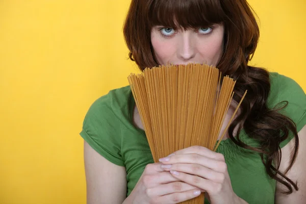 Beautiful brunette holding spaghettis isolated on yellow — Stock Photo, Image