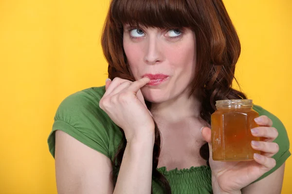 Frau probiert Honig aus dem Glas — Stockfoto