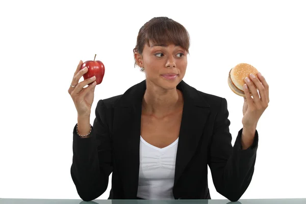 Woman choosing between burger and apple — Stock Photo, Image