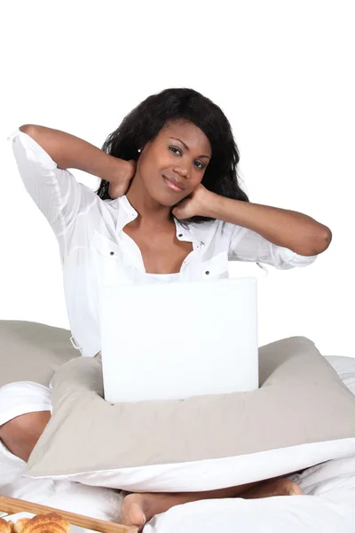 Mulher esfregando o pescoço enquanto usa um laptop em sua cama — Fotografia de Stock