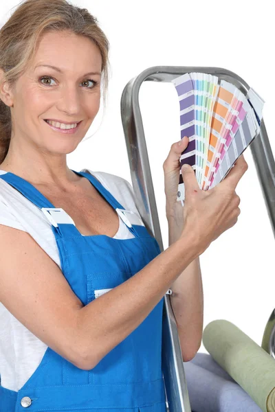 Eine Frau in Latzhose, die uns eine Reihe von Farben zeigt. — Stockfoto