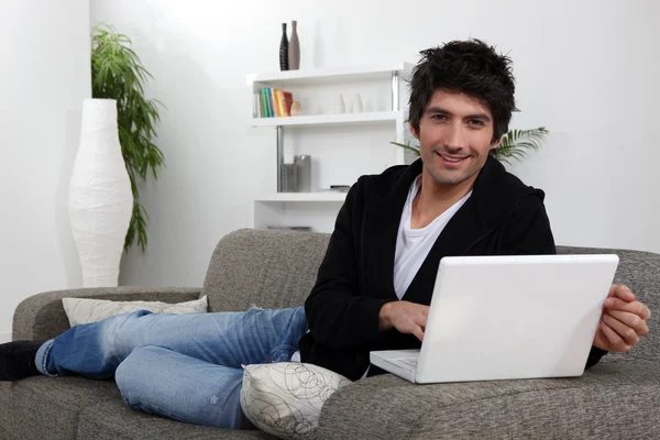 Mann liegt mit Computer auf Sofa — Stockfoto