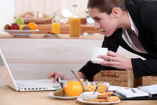 Geschäftsfrau blickt beim Frühstück auf Laptop — Stockfoto