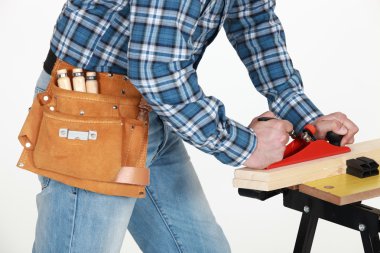Tradesman using a plane to smooth a plank of wood clipart
