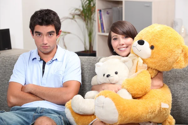 Νεαρό ζευγάρι με αρκουδάκια σε ένα καναπέ — Φωτογραφία Αρχείου