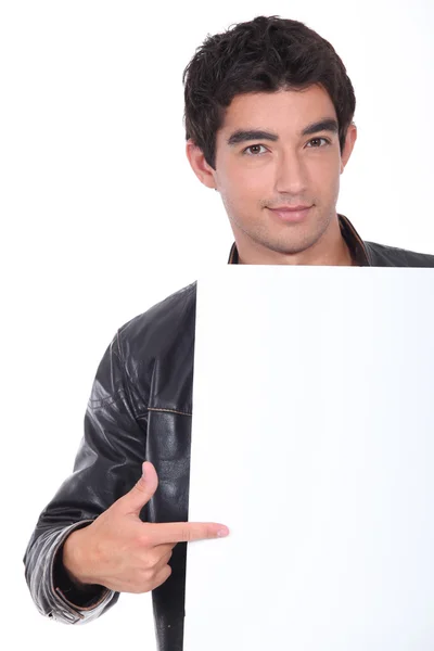 Młody człowiek wskazującego afisz biały — Zdjęcie stockowe