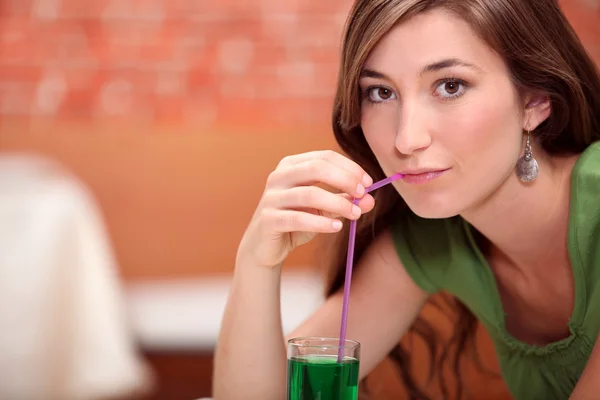 Woman drinking green cocktail — Stock Photo, Image