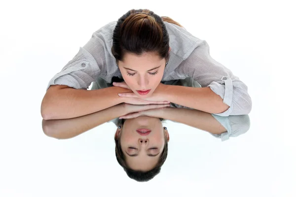 Femme les yeux fermés appuyée sur une table en miroir — Photo