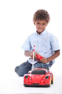 Little boy at play with remote-controlled racing car clipart