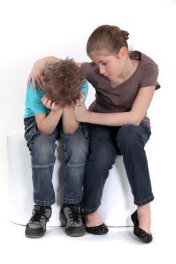 Sister comforting her little brother. clipart