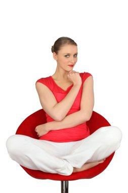 Pensive blond sat cross-legged on swivel chair clipart