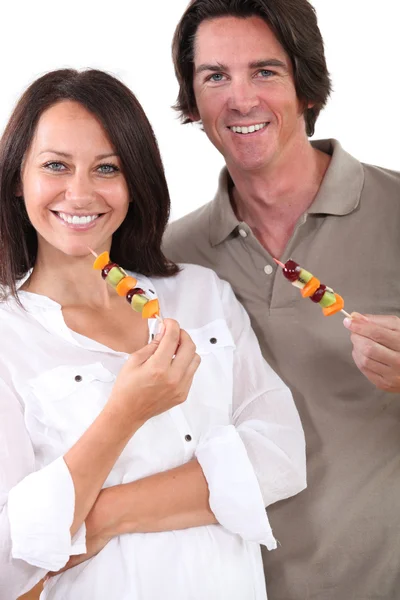 Portrait of a couple with fruit brochettes — Stock Photo, Image