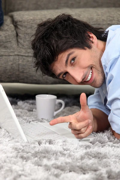 Man lade på en matta med laptop — Stockfoto