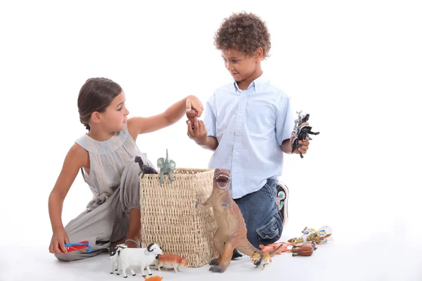 Brother and sister playing with toy animals — Stock Photo, Image
