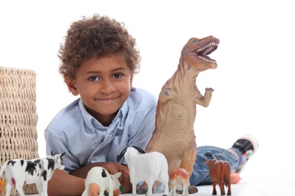 Мальчик играет с игрушечным динозавром и коллекцией домашних животных — стоковое фото