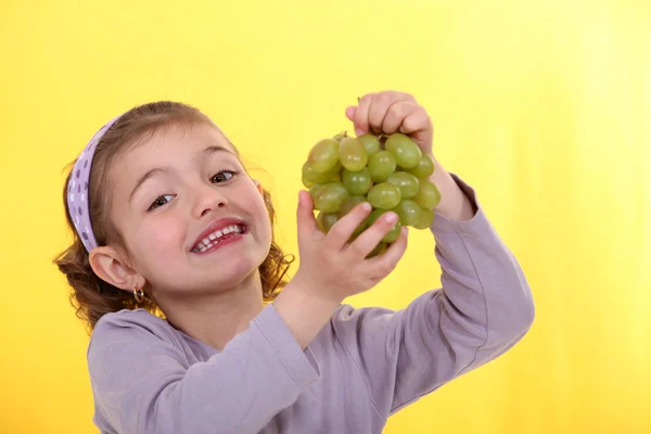 Маленькая девочка держит кучу зеленого винограда — стоковое фото