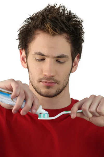 Jongeman knijpt tandpasta op een borstel — Stockfoto