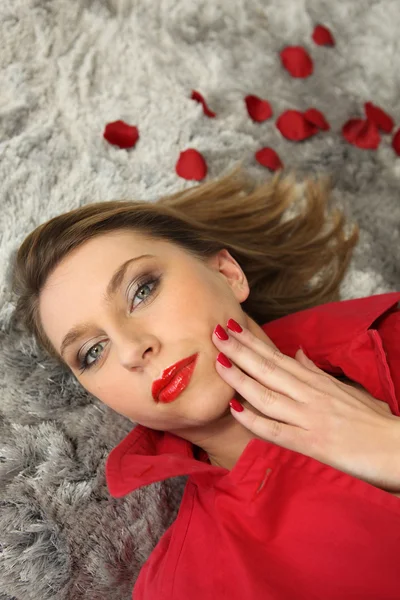Жінка лежить в оточенні пелюсток троянд — стокове фото