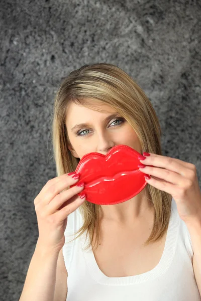 Mulher loira segurando lábios novidade na frente de seu rosto — Fotografia de Stock