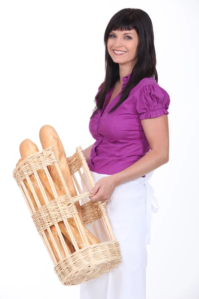 Vrouwelijke bakkerij werknemer met mandje van brood — Stockfoto