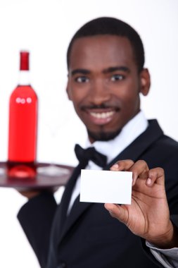 Wine waiter holding forth a business card left blank for your details clipart